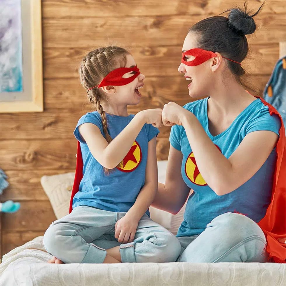 Mutter und Tochter mit Superman-Verkleidung grÃ¼ÃŸen sich glÃ¼cklich mit der Faust