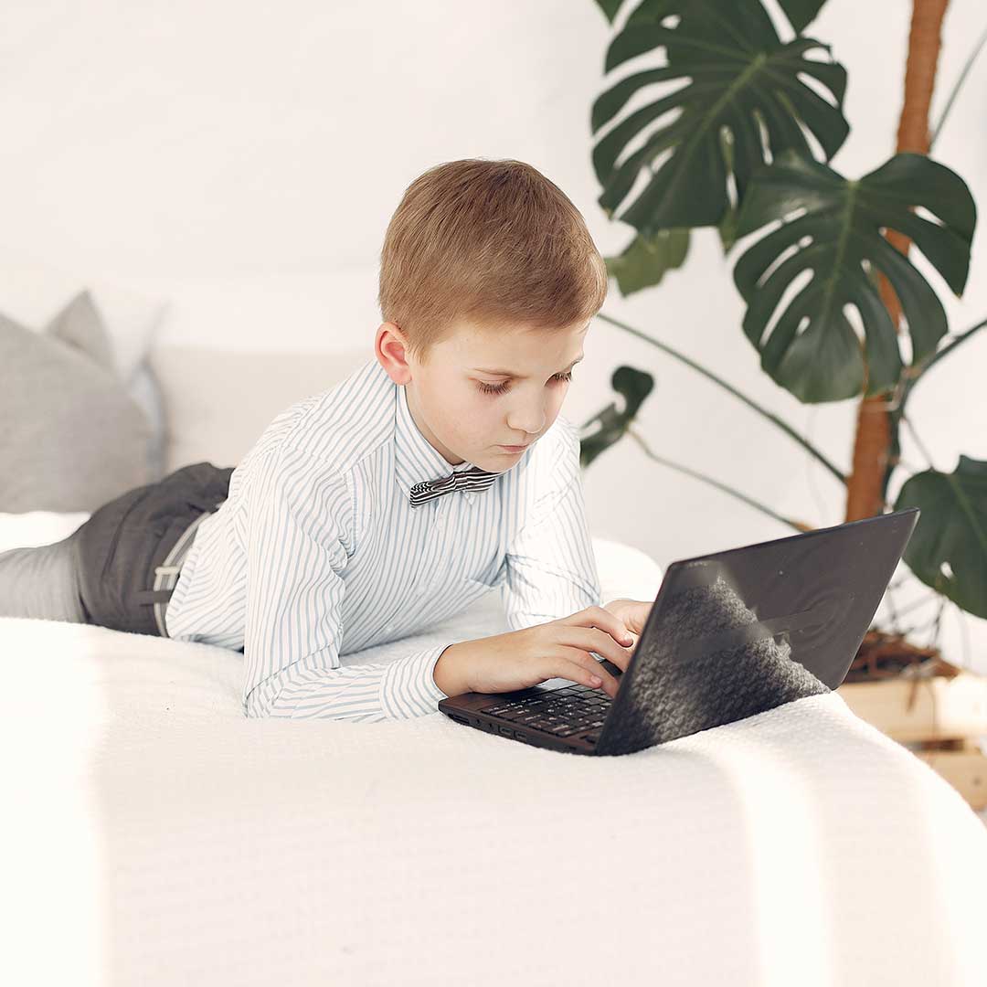 Junge arbeitet im Bett am Laptop